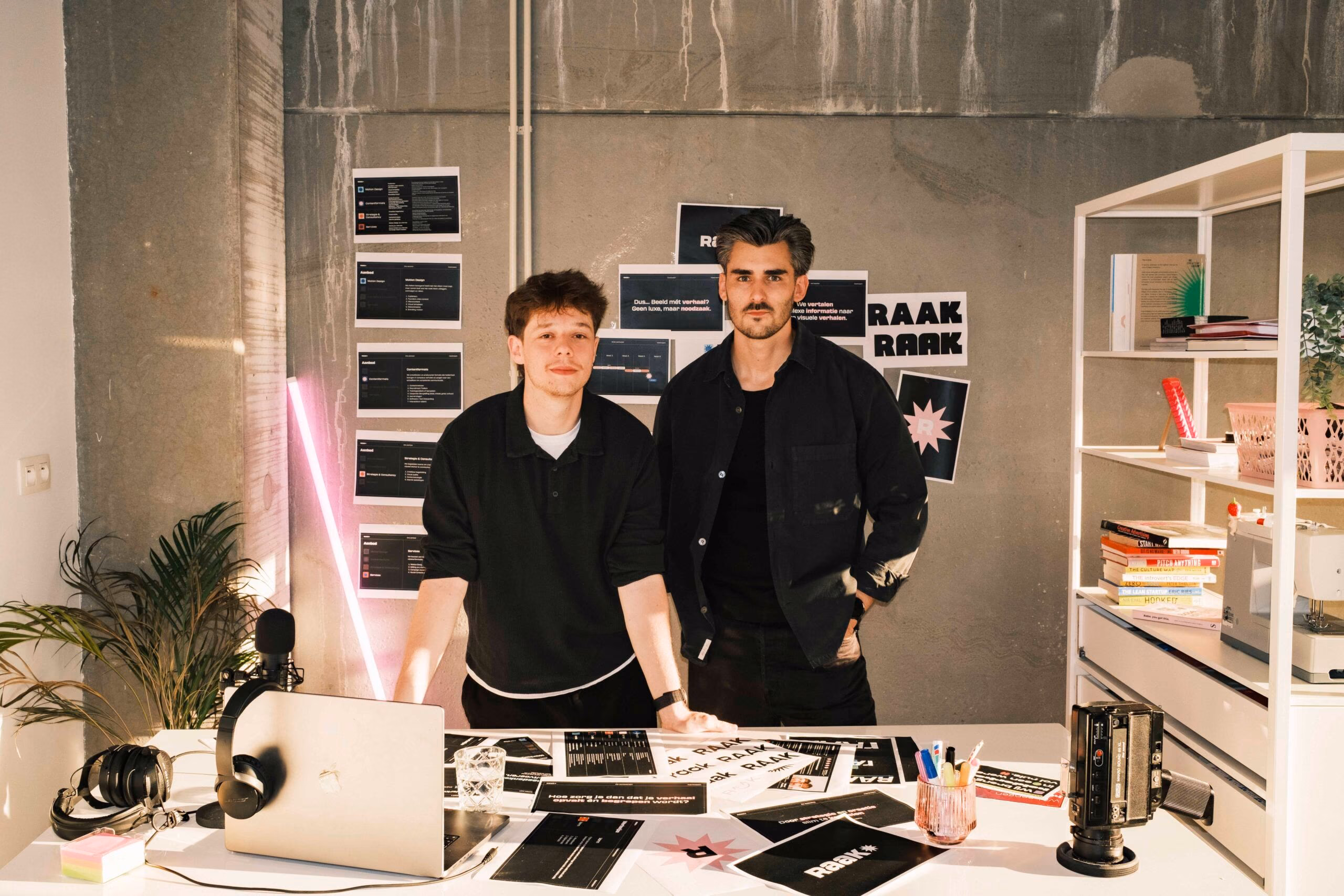 Casper Coomans en Niels Wouters achter een tafel vol Raaaak-schetsen in hun studio